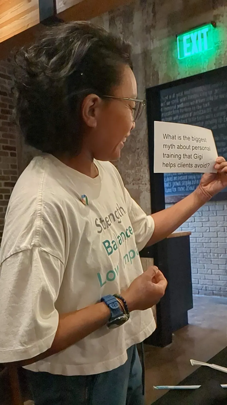 Gigi smiling while presenting at a networking event, holding a question card